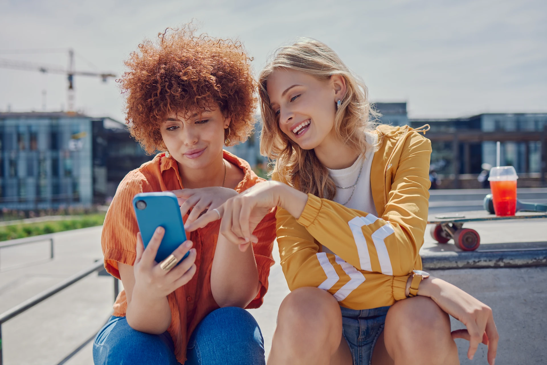 Zwei Skater-Girls lassen ihr Board im Hintergrund links liegen und checken am Handy die News der Volkswagen Bank.